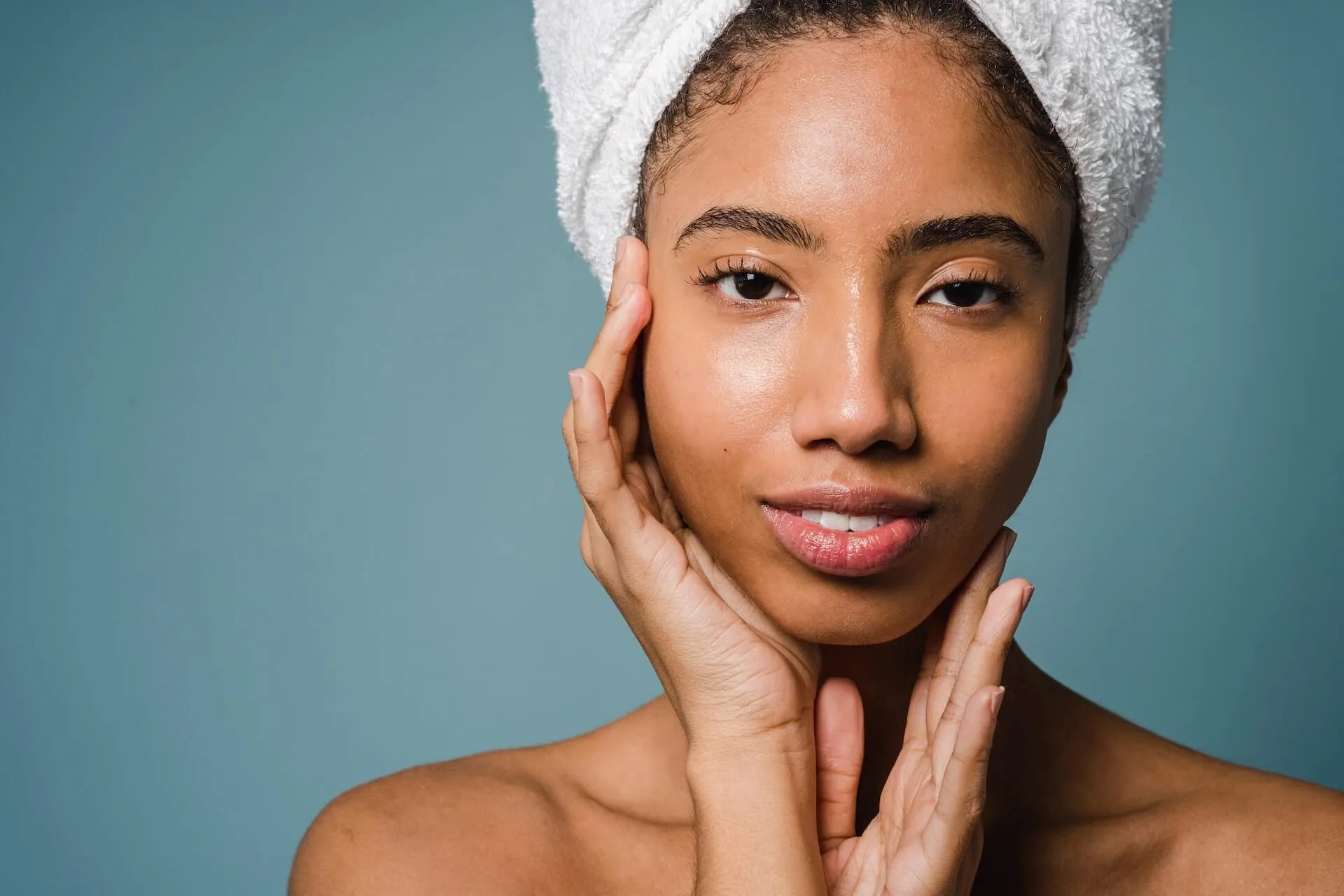 A woman with a bright, glowing complexion touching her smooth skin after a Rejuvenating Enzyme Peel.