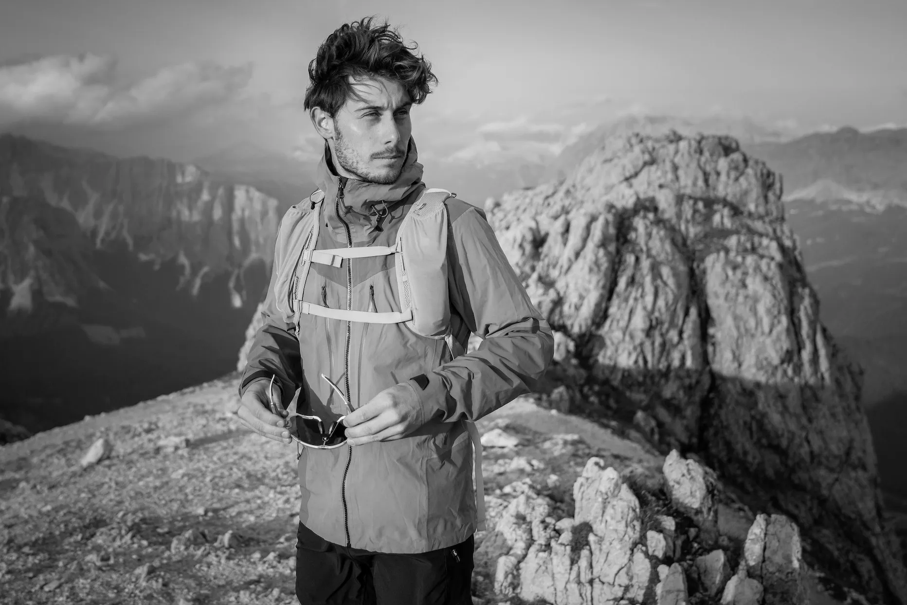Schwarz-weiß-Foto eines Mannes auf einem Felsen mit Berglandschaft