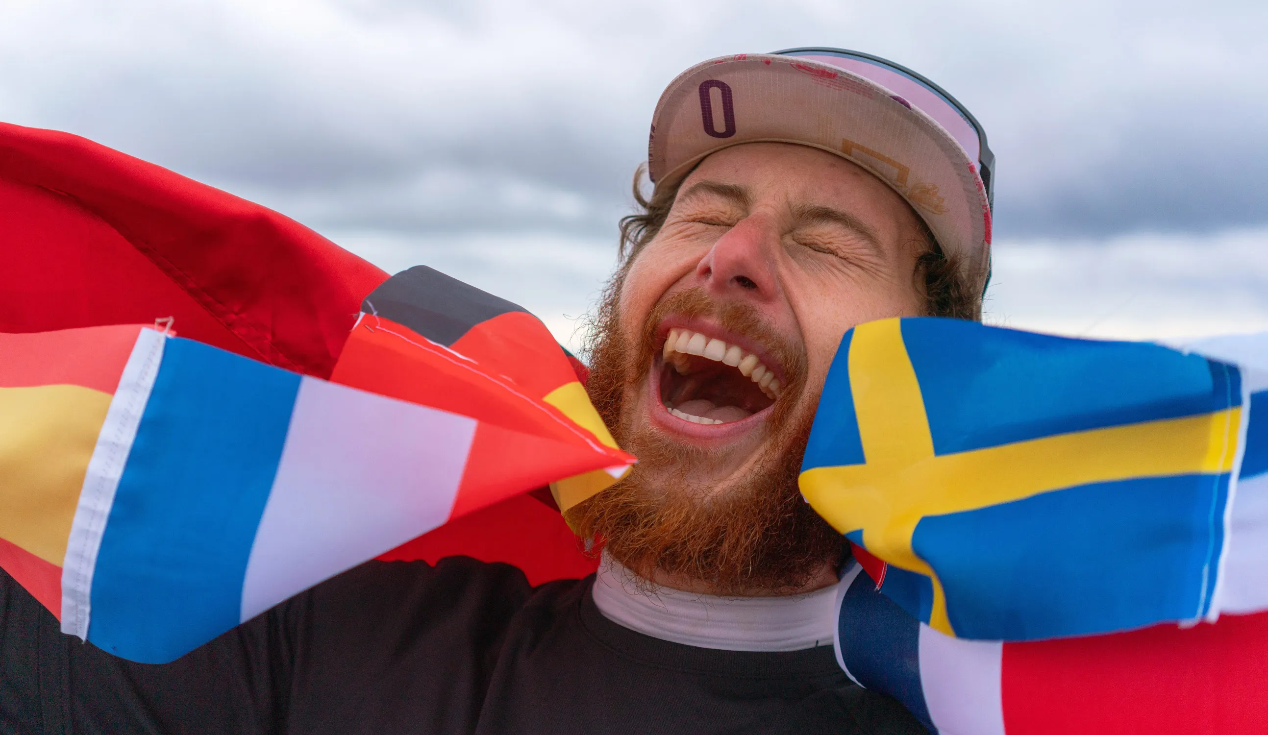 Person jubelt und hält mehrere Landesflaggen hoch