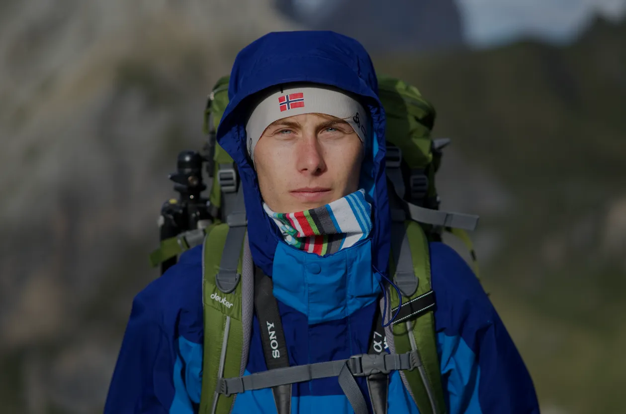 Person mit blauer Kaputze und Rucksack in felsigem Gebirge