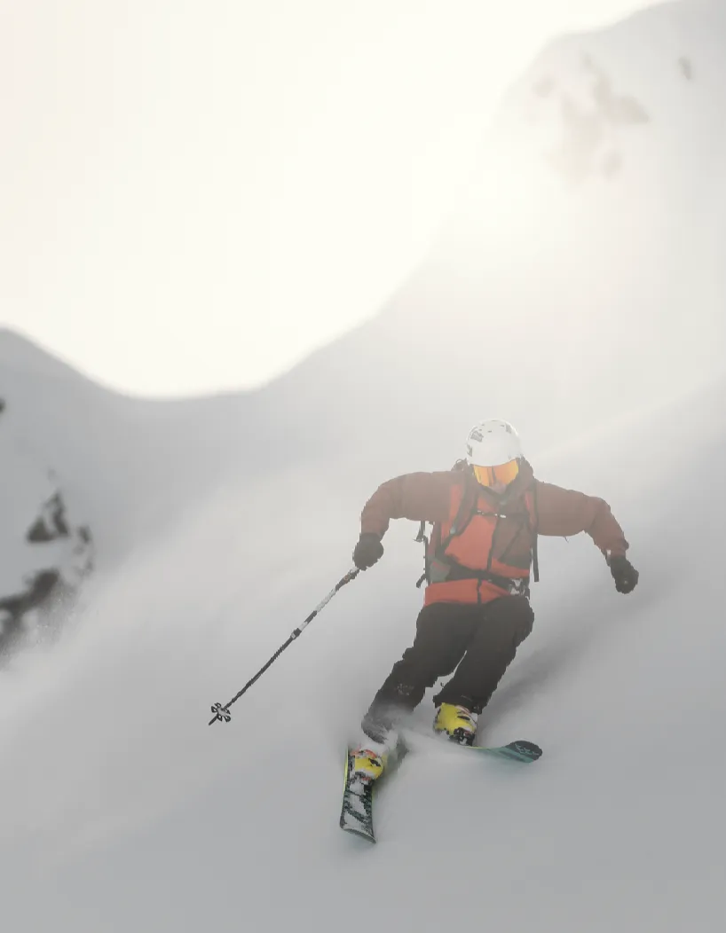 Skifahrer fährt dynamisch durch Pulverschnee bei diffusem Licht