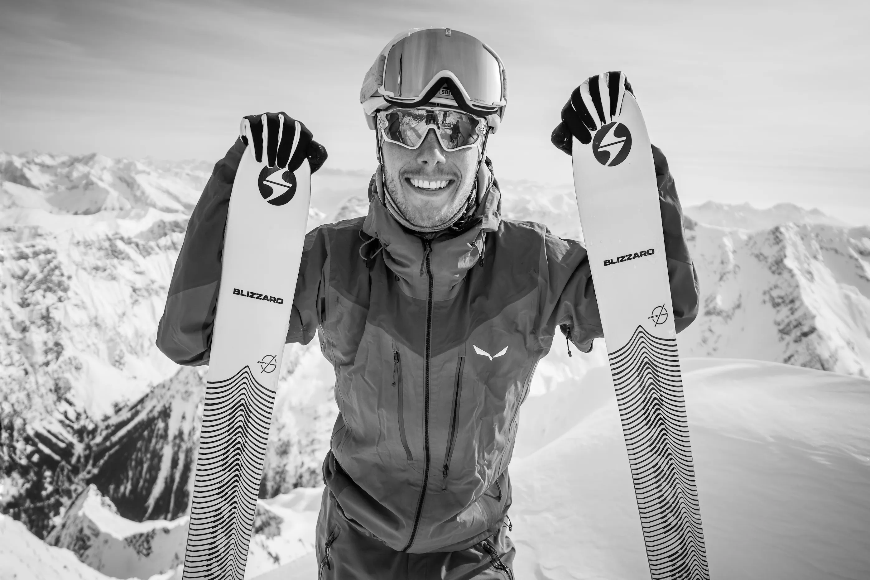 Sportliche Person posiert lachend mit erhobenen Armen im Schnee