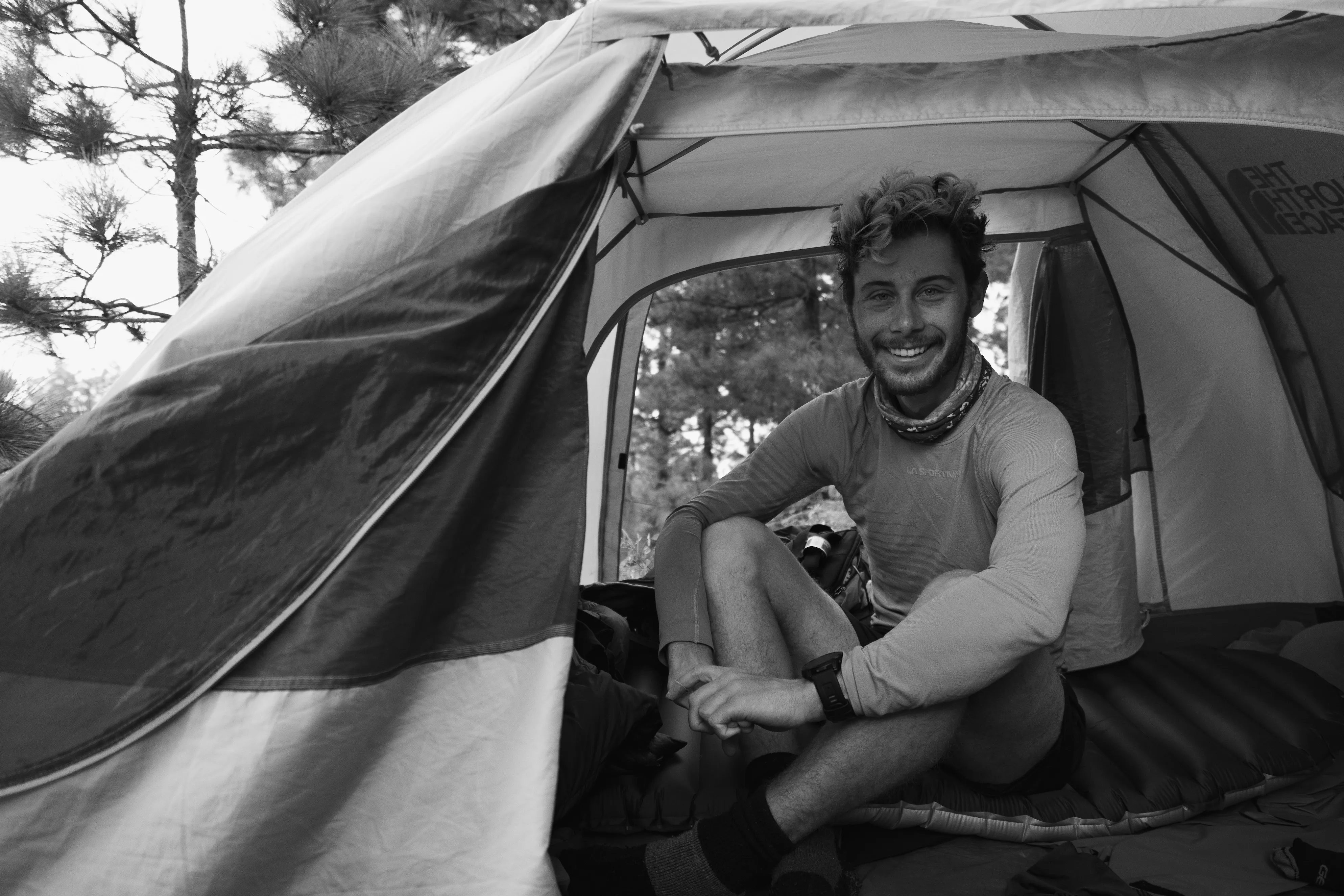 Person sitzt im geöffneten Zelt, Camping-Szene in schwarz-weiß