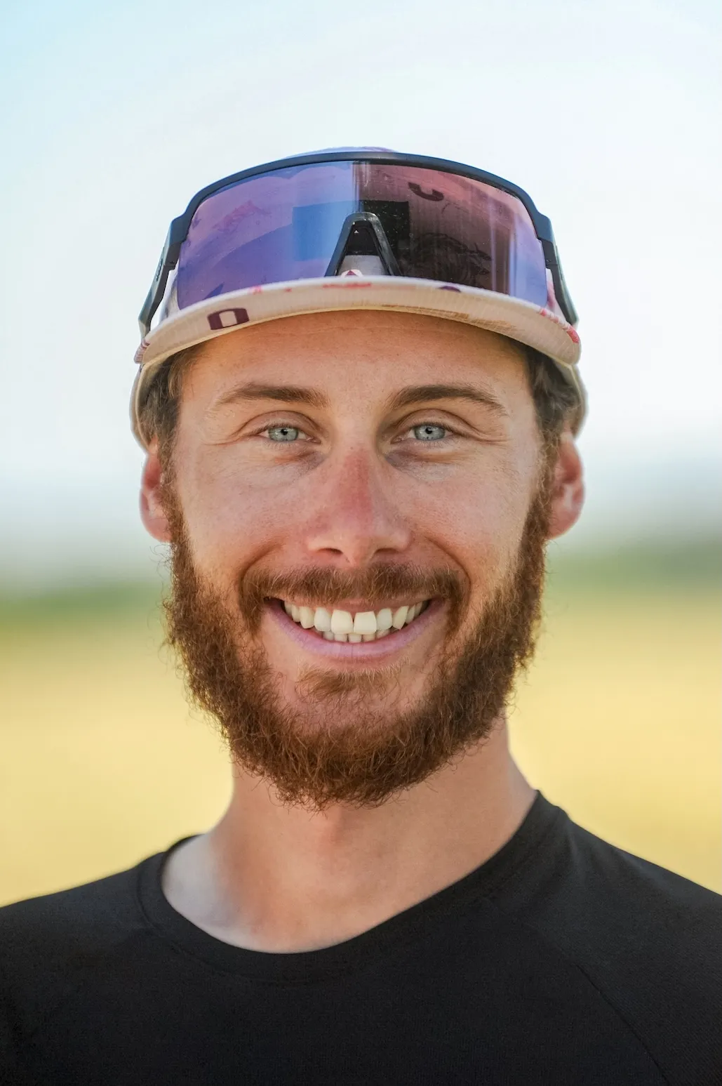 Porträt einer lächelnden Person mit Sonnenbrille, im Freien aufgenommen