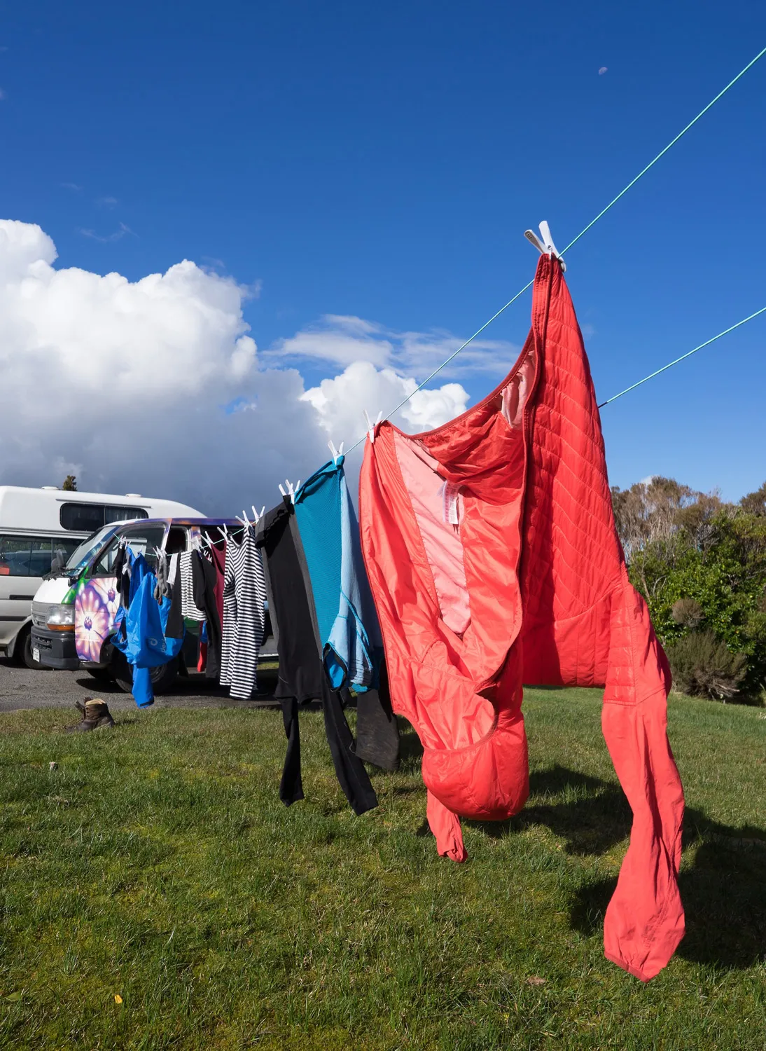 Person hängt rote Kleidung oder Stoffe an einer Leine im Freien auf