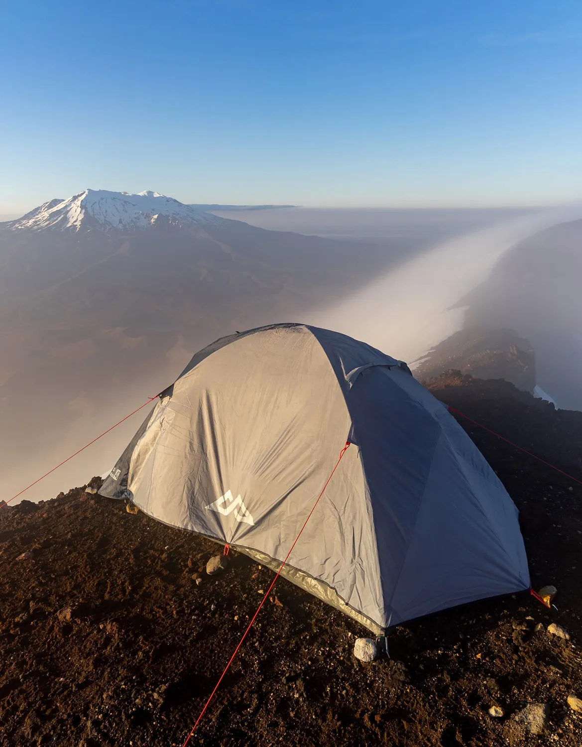 Zelt steht auf felsigem Bergkamm bei Sonnenaufgang