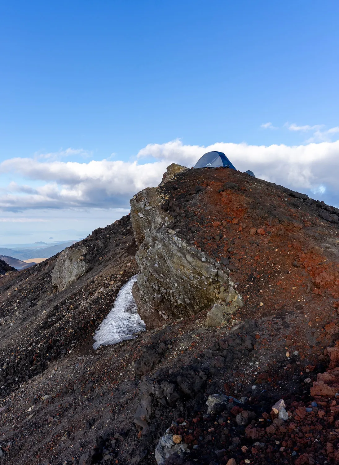 Bunter, felsiger Bergkamm bei Sonnenlicht mit Zelt