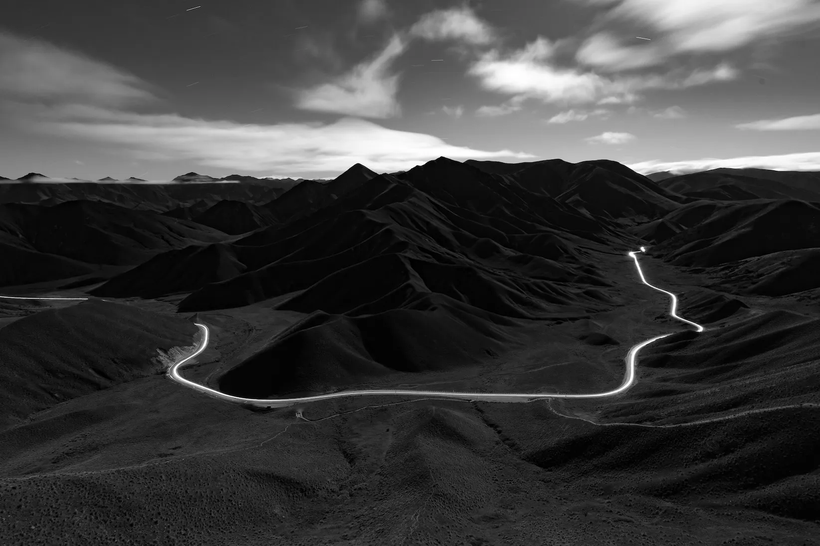 Nachtaufnahme von Landschaft mit erheltter Straße in der Nacht