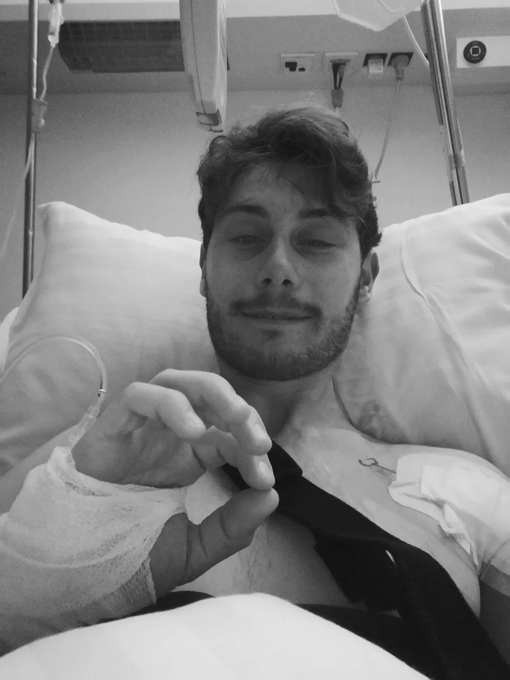 Mann liegt im Krankenhausbett und zeigt Daumen hoch