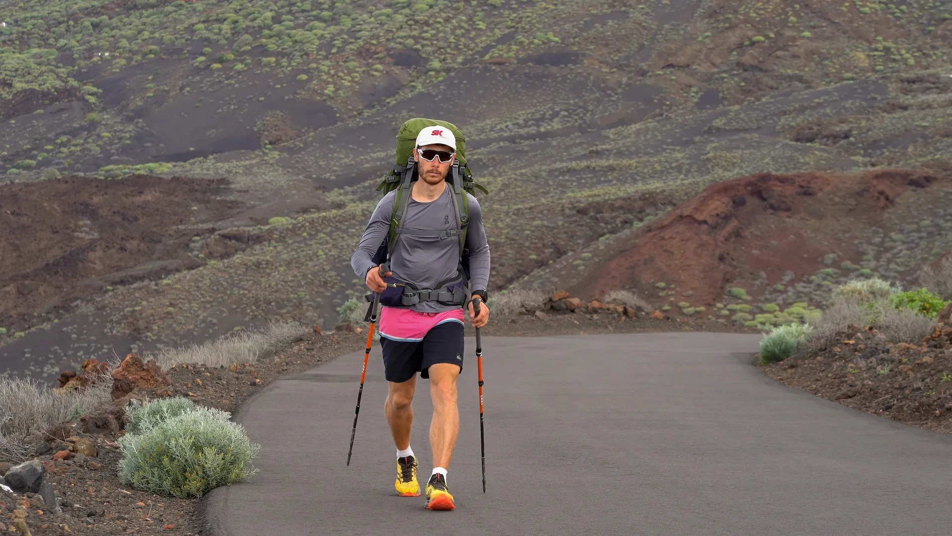 Mann beim Weitwandern auf einer Straße in vulkanischer Landschaft