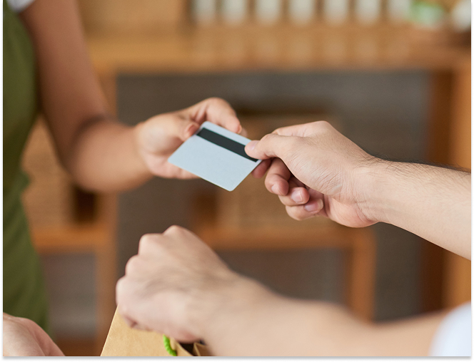 Close-up of two people exchanging a credit card over a counter.