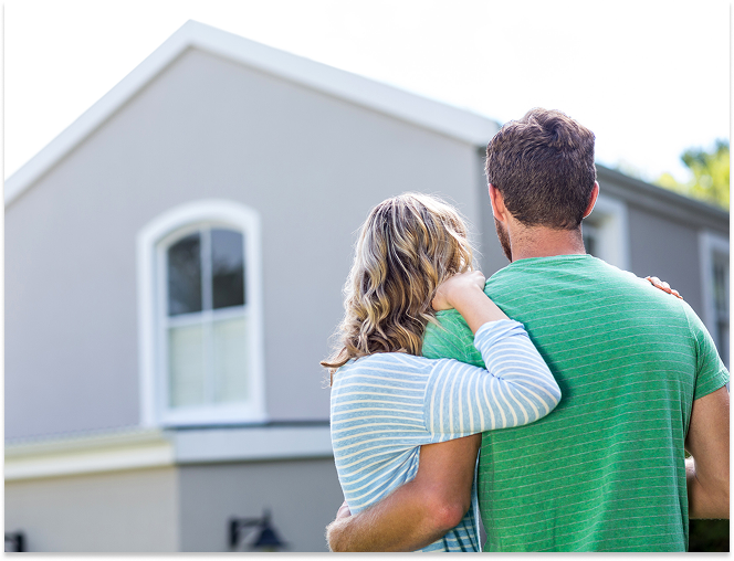 Couple with arms around each other looking at a suburban house.