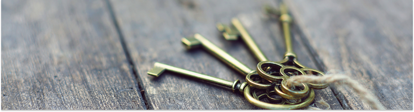 A set of vintage brass keys tied together with a piece of twine on a rustic wooden surface.