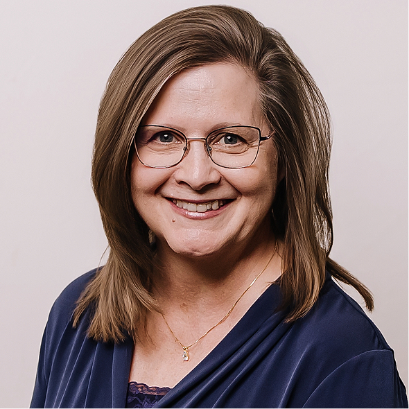 Smiling woman with shoulder-length brown hair wearing glasses and a black top with a decorative necklace.