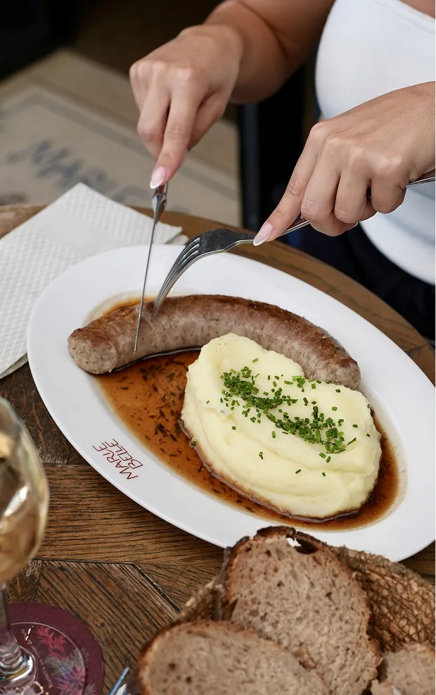 Serveur découpant un steak avec purée de pommes de terre