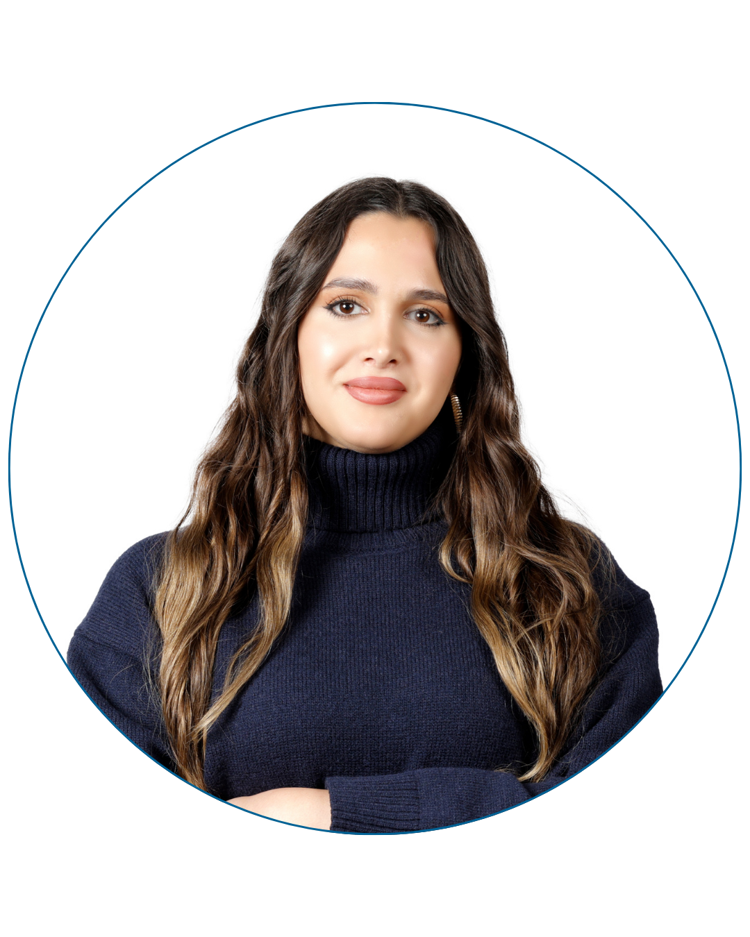 Young woman with long wavy brown hair wearing a navy blue turtleneck sweater, smiling slightly with arms crossed.