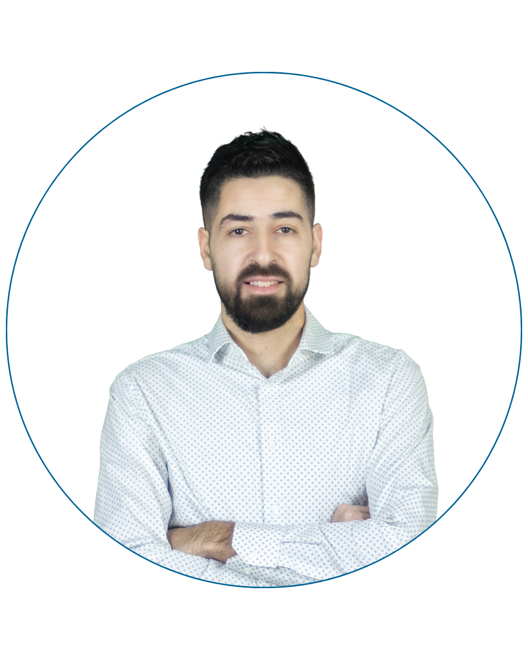 Man with black hair and beard wearing a white shirt with blue dots, smiling with arms crossed.