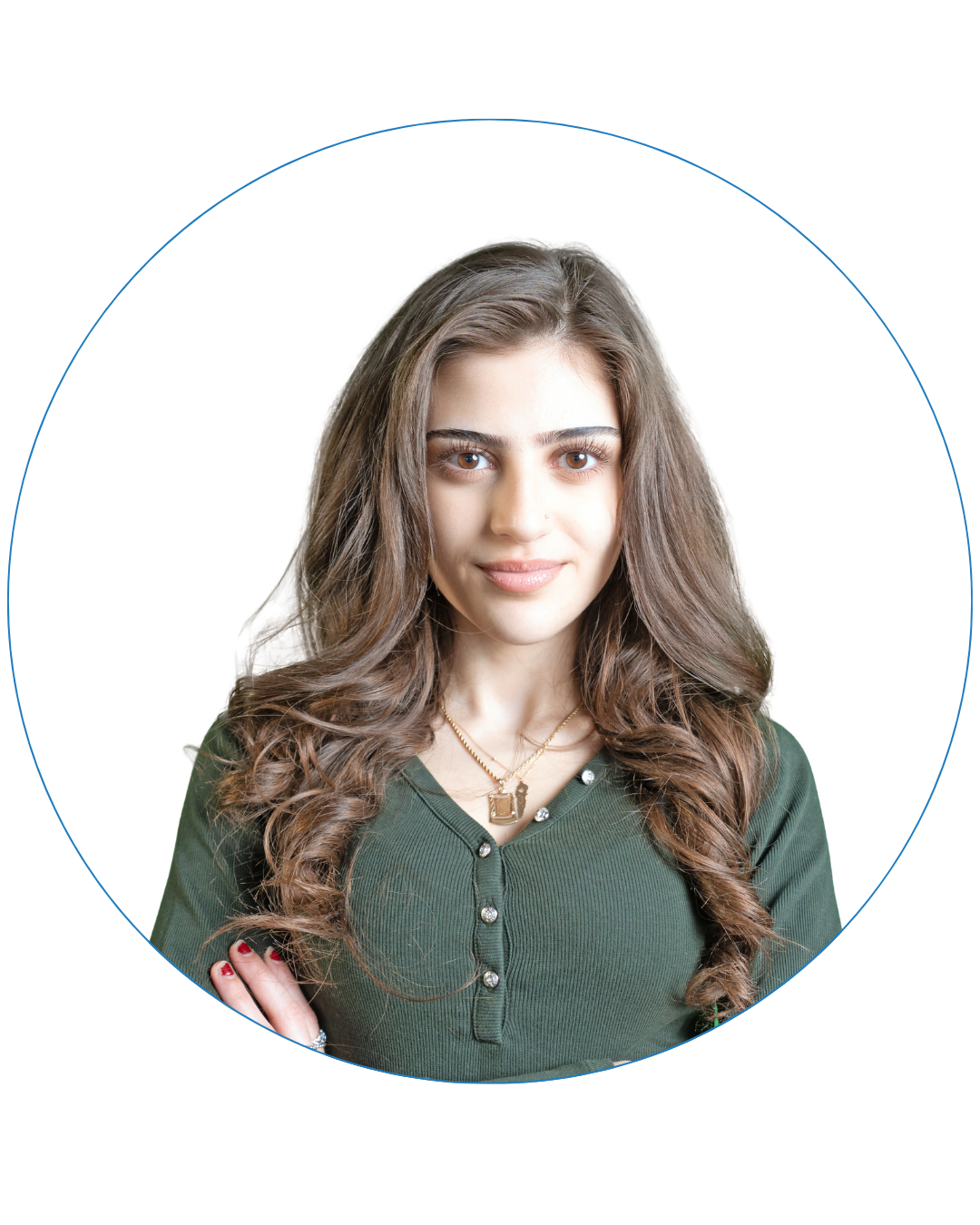 Young woman with long wavy brown hair wearing a green buttoned top and gold necklaces, smiling with arms crossed.