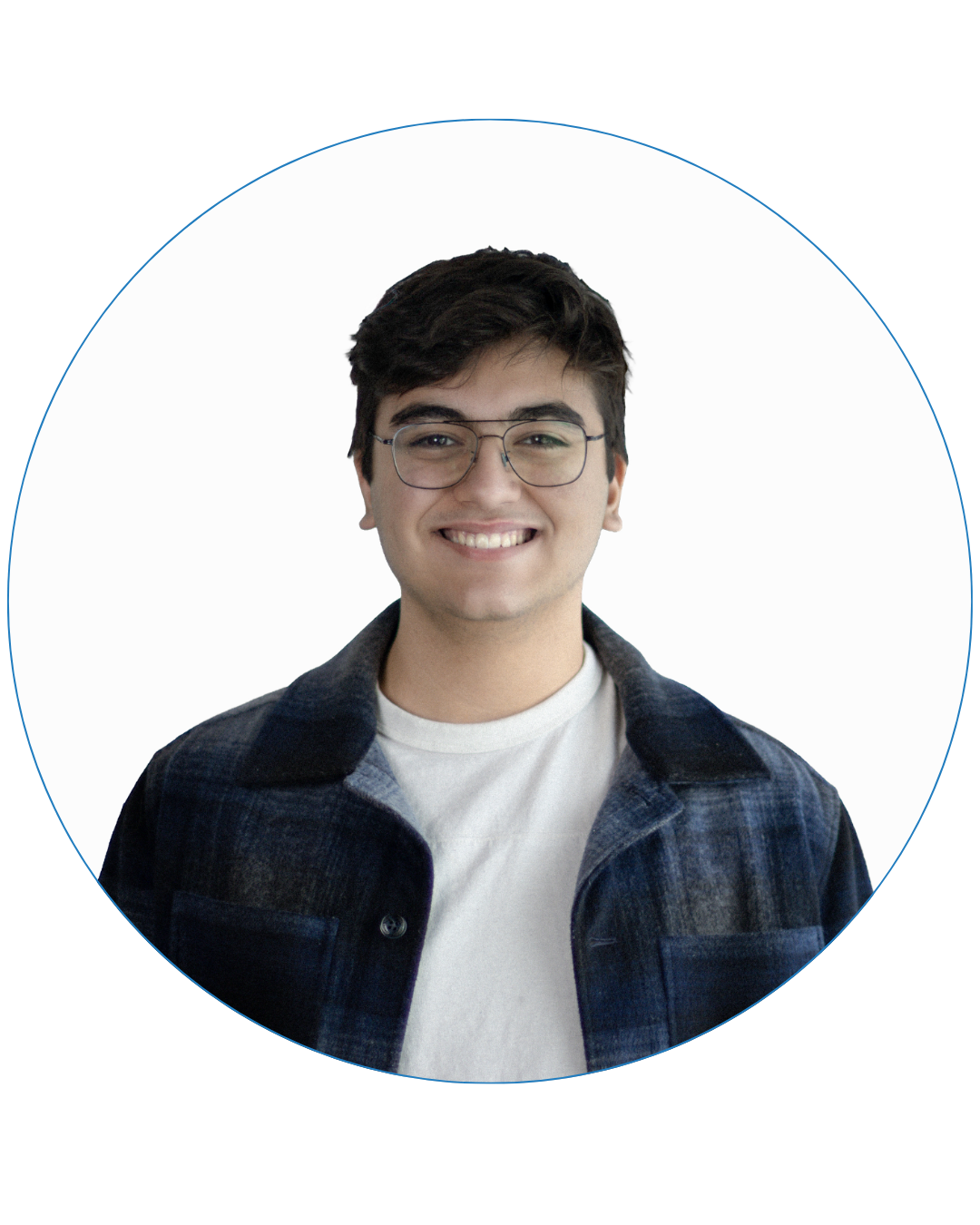 Smiling young man with dark hair and glasses wearing a blue plaid jacket over a white shirt.