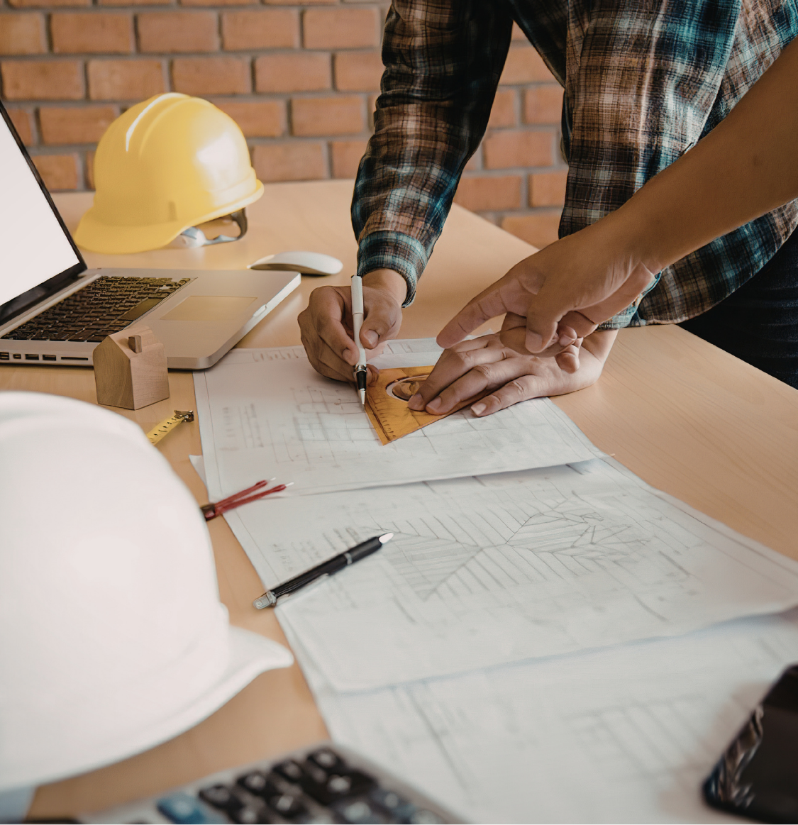 Construction workers wearing safety gear shaking hands outdoors under a clear sky.