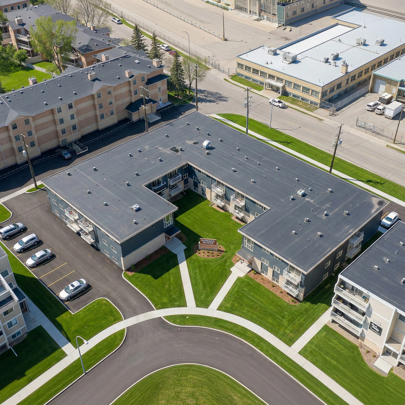 Six-story brick apartment building with balconies on a snowy ground under a clear blue sky.