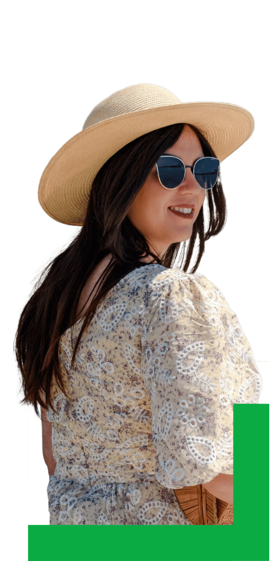 A person wearing a hat, off-shoulder blouse, and denim shorts stands with a suitcase, holding a passport and a camera.