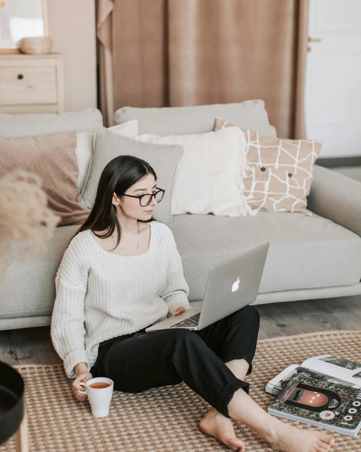 Women leaning against sofa with cup and computer