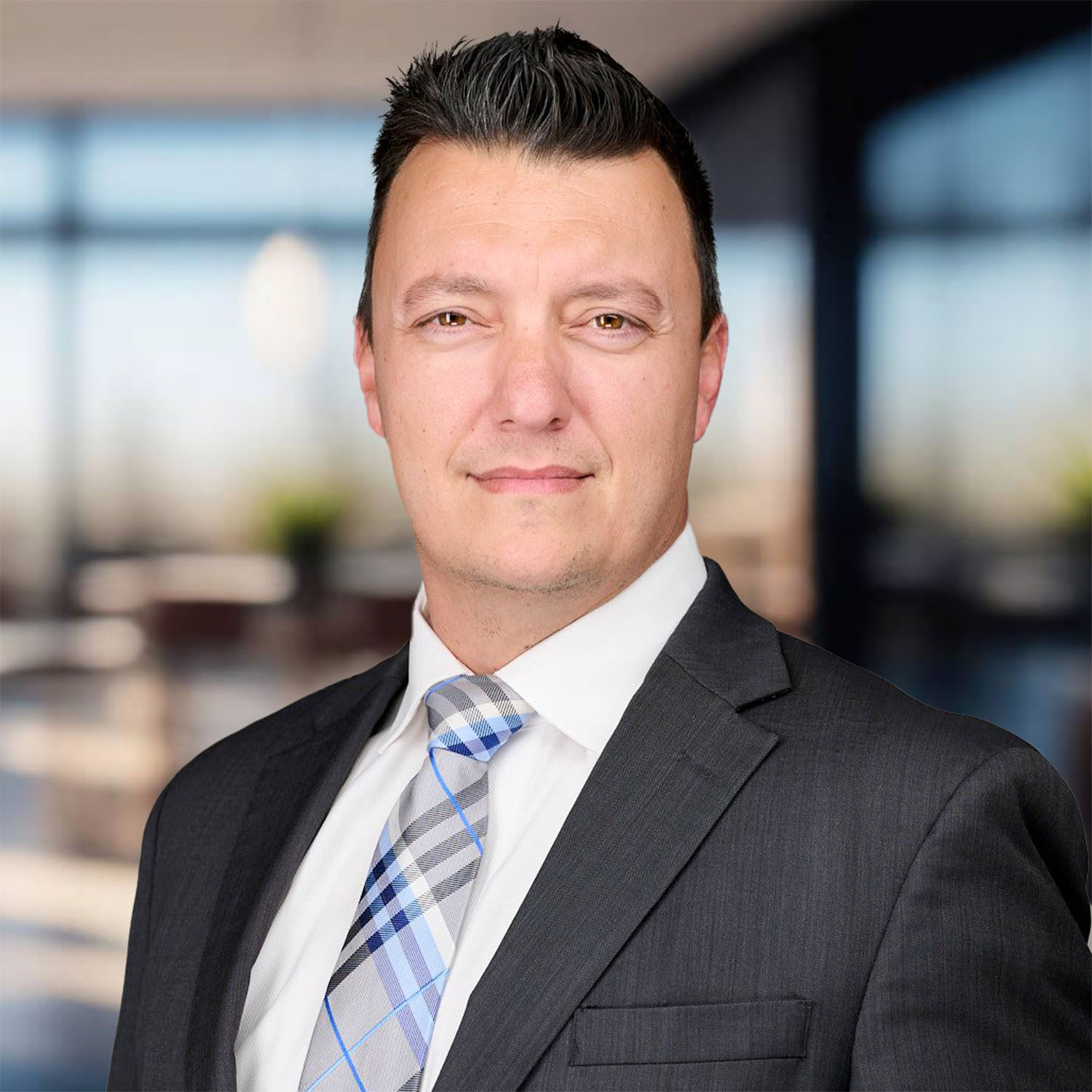 Man in suit and tie standing in bright office setting.