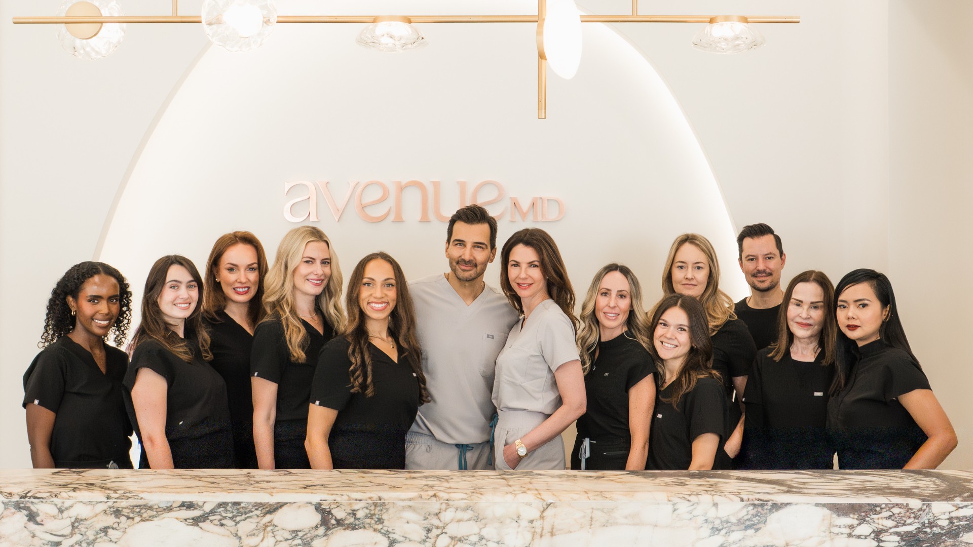 AvenueMD's team posing in a bright, modern office with logo in background.
