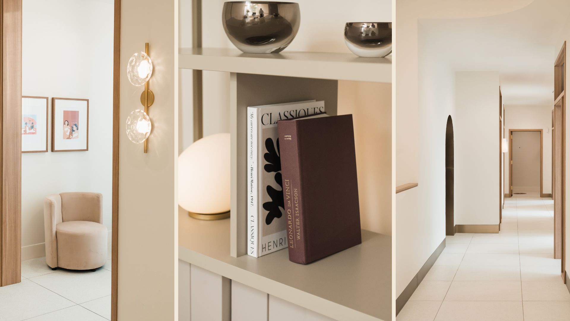 Minimalist hallway with white tiled floor, wooden door frames, beige armchair with framed art, and a shelf holding decorative books and metallic bowls.
