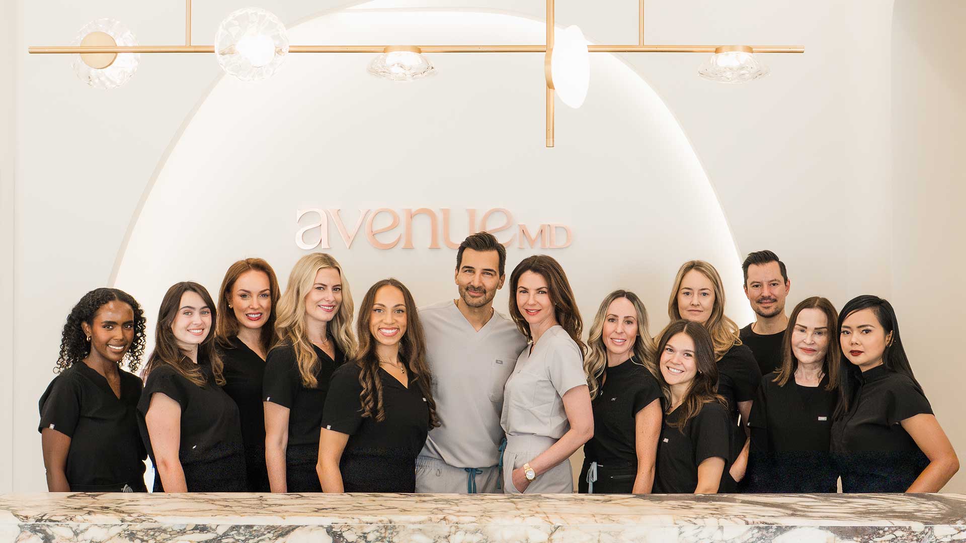 AvenueMD's team posing in a bright, modern office with logo in background.