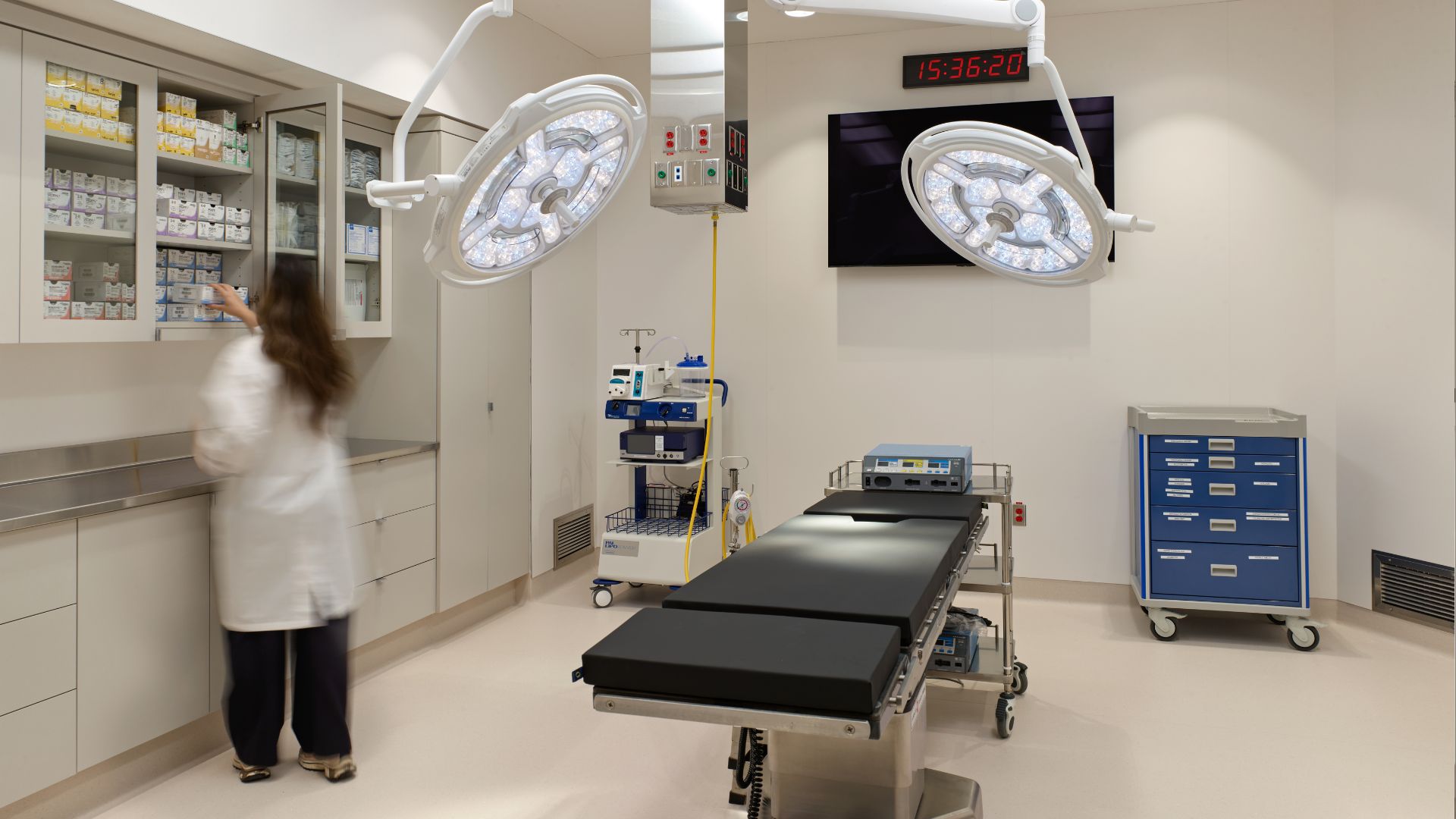 Brightly lit clean operating room with table and nurse working at counter