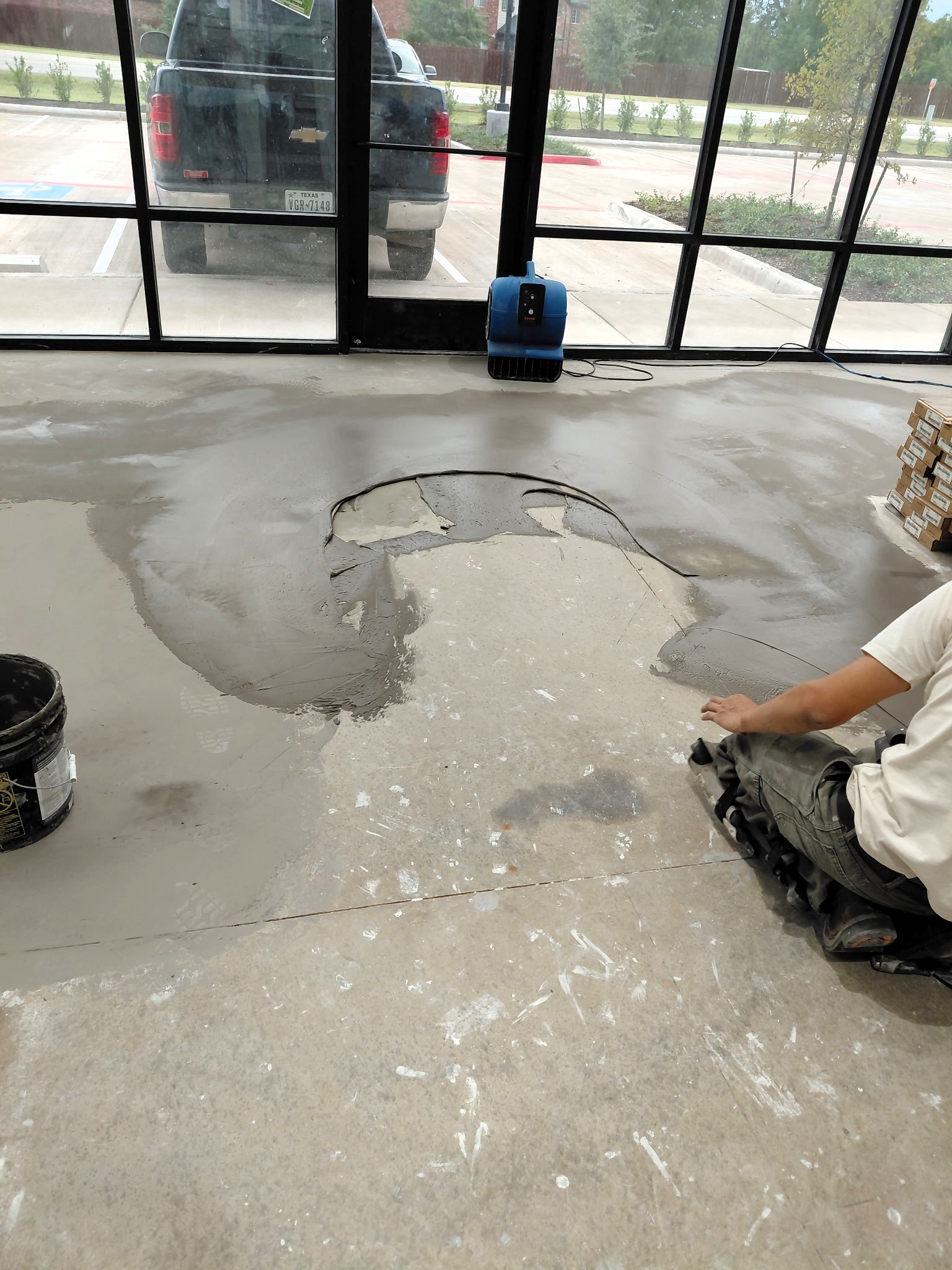 Applying self-leveling compound on concrete floor to prepare for engineered wood installation in Houston.