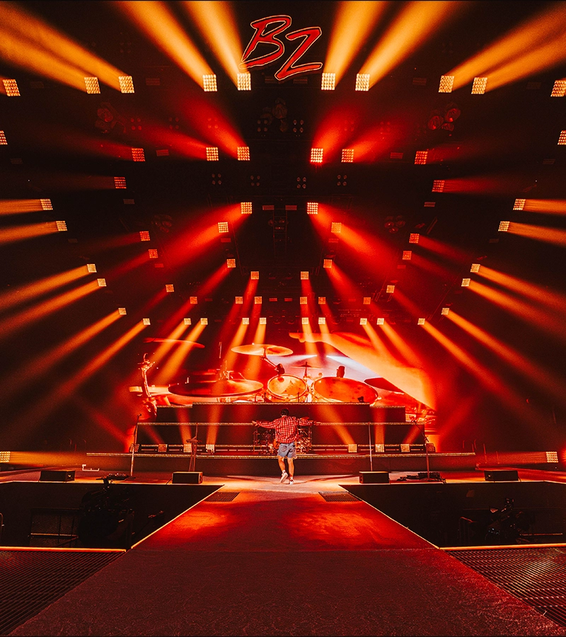 A big orange concert stage with red and orange beams in the air.