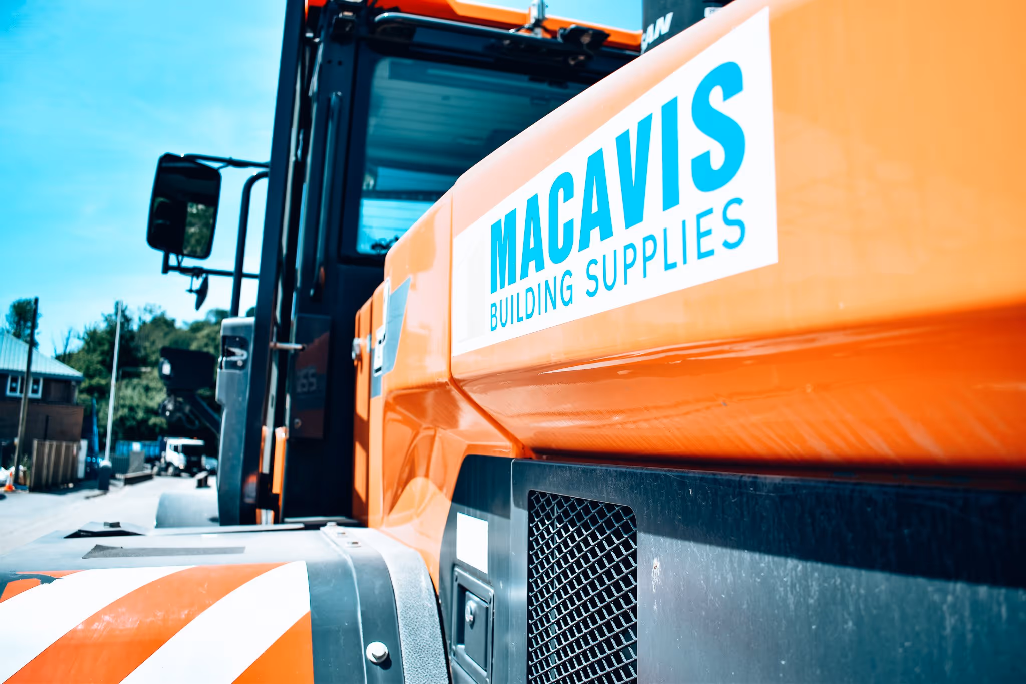 Orange Macavis Building Supplies truck parked on urban street