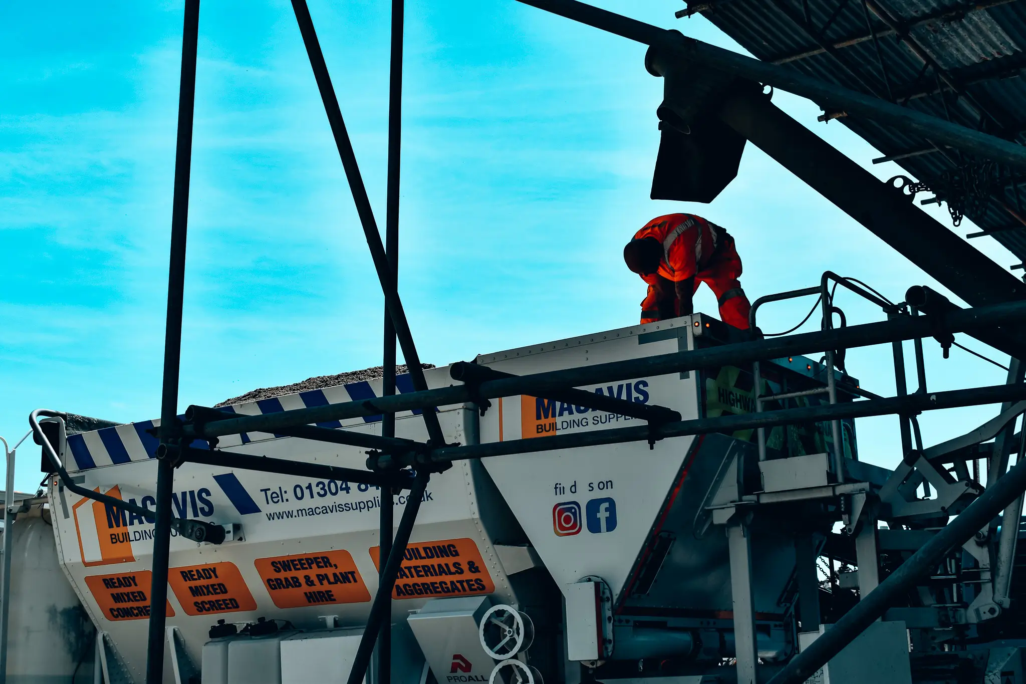 Worker in red safety gear on Macvis building supplies concrete mixer