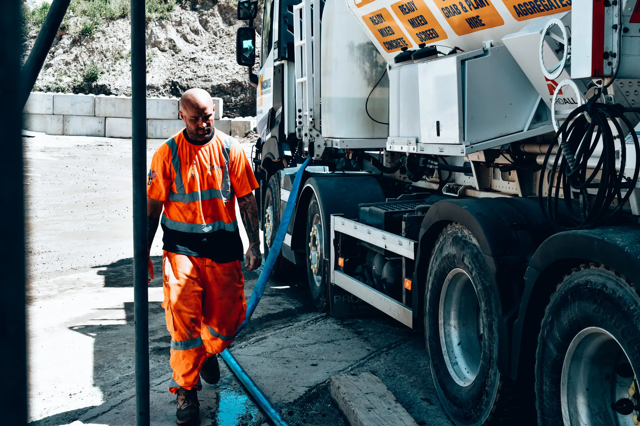 Worker in orange safety vest standing next to large industrial truck