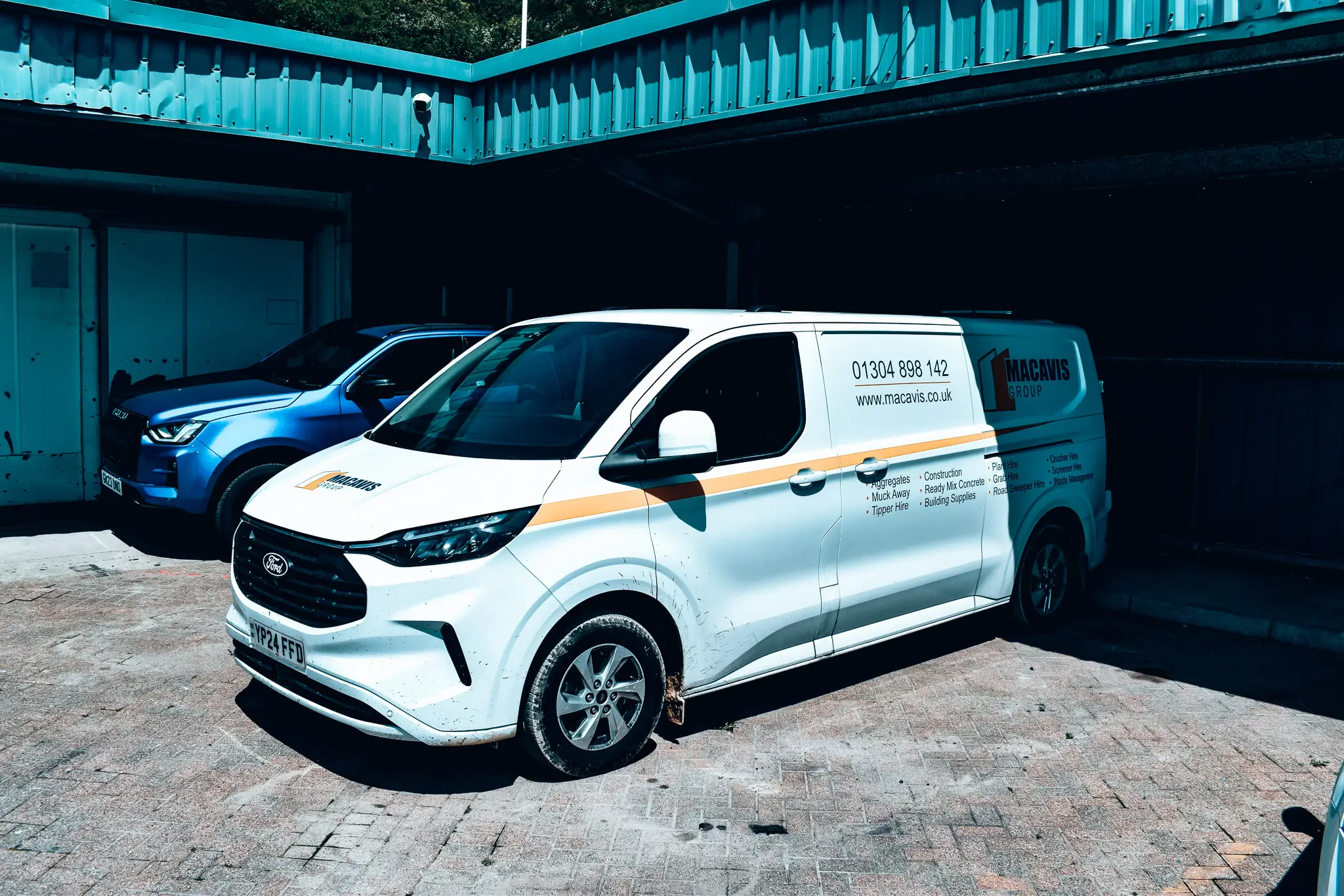 White Macavis Group Ford van parked in industrial building exterior