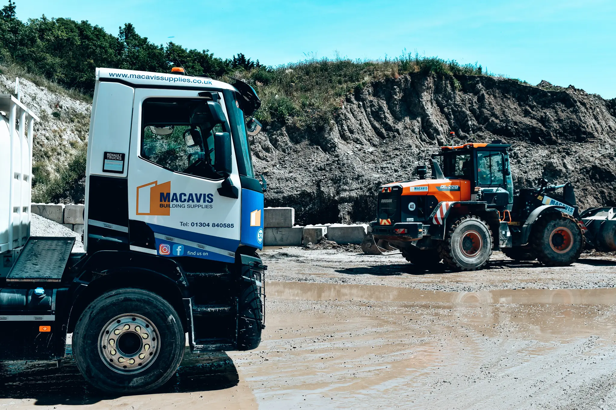 Macavis Building Supplies truck and loader in quarry with rocky background