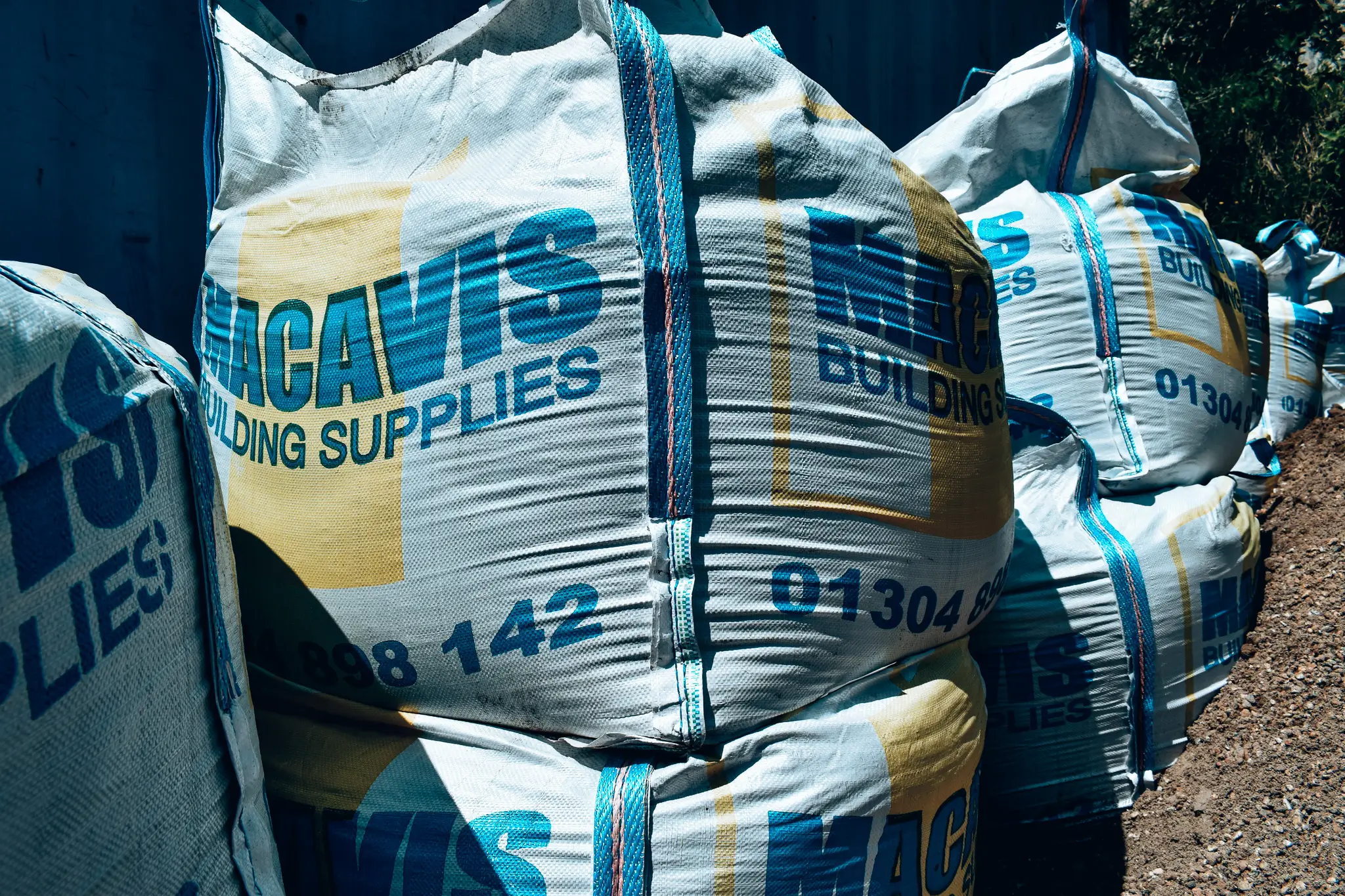 Stacked Macadam building supplies bags with blue and white branding
