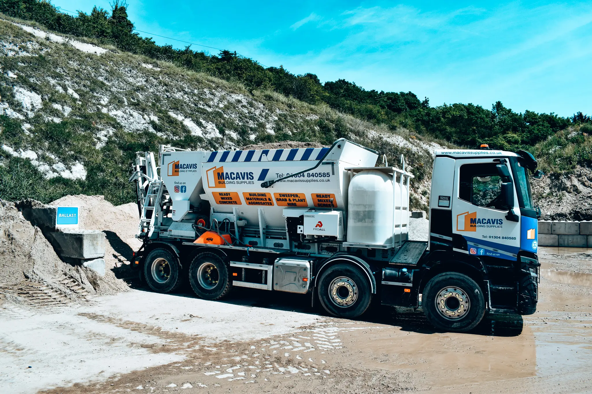 Macavis building supplies truck parked at quarry with ballast and rocky background