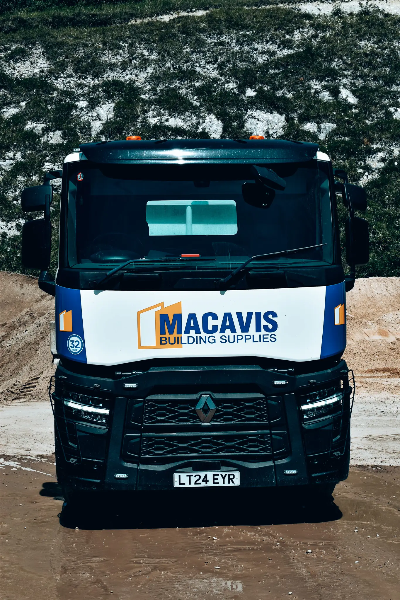 Macavis Building Supplies truck parked on muddy construction site