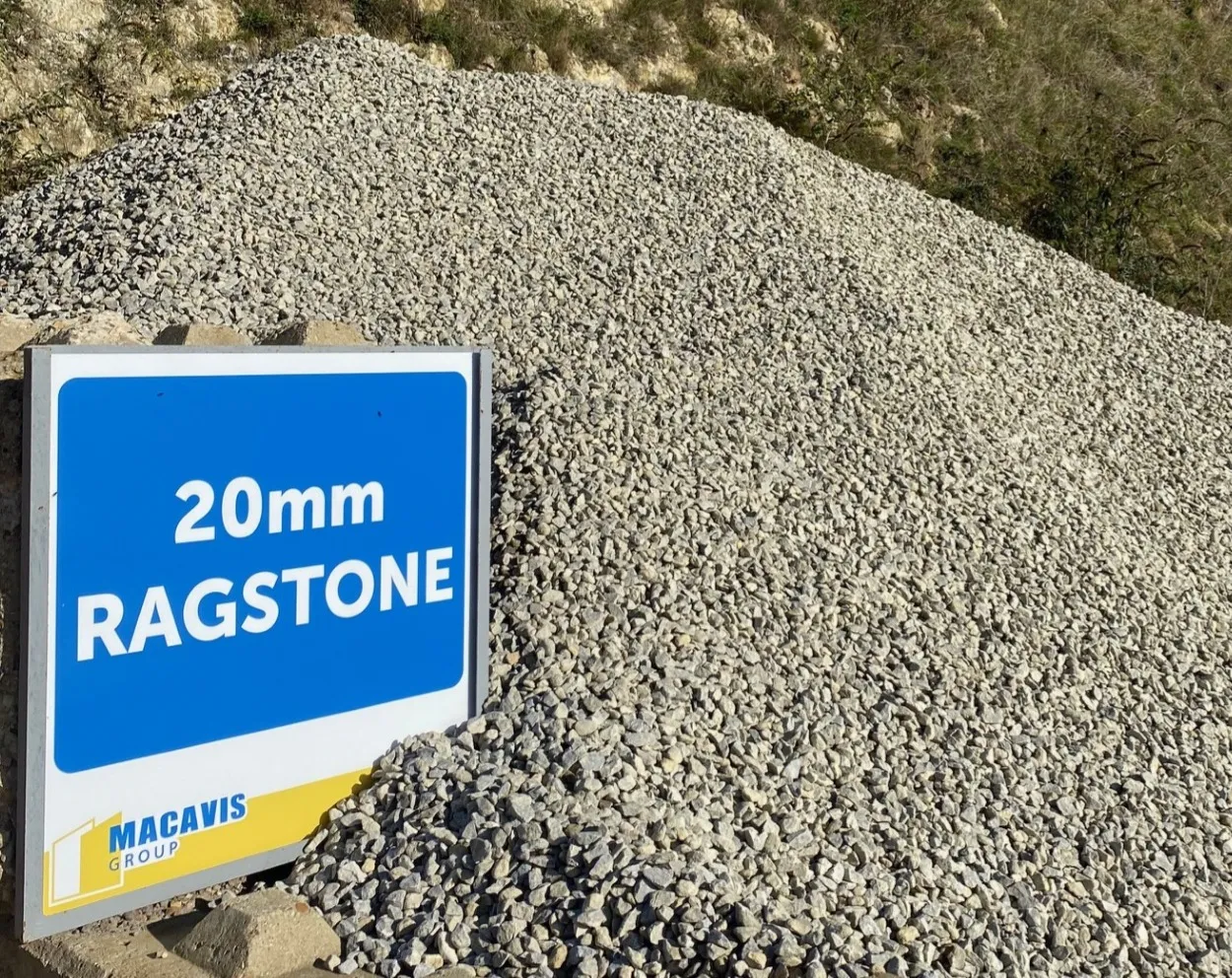 Large pile of 20mm ragstone gravel next to a sign labeled '20mm Ragstone' by Macavis Group.