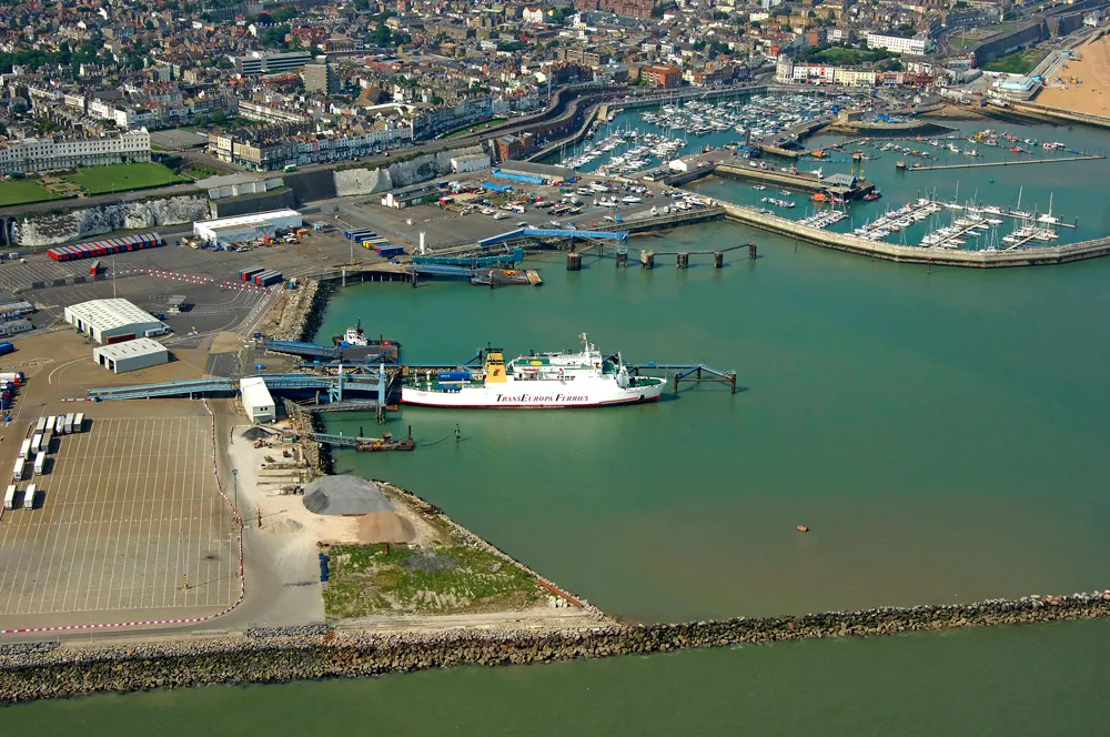 Aerial view of a busy port with a TransEuropa ferry docked and a harbor marina with boats and buildings nearby.