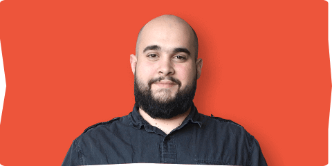 A man with a beard wearing a black shirt, looking directly at the camera with a neutral expression.