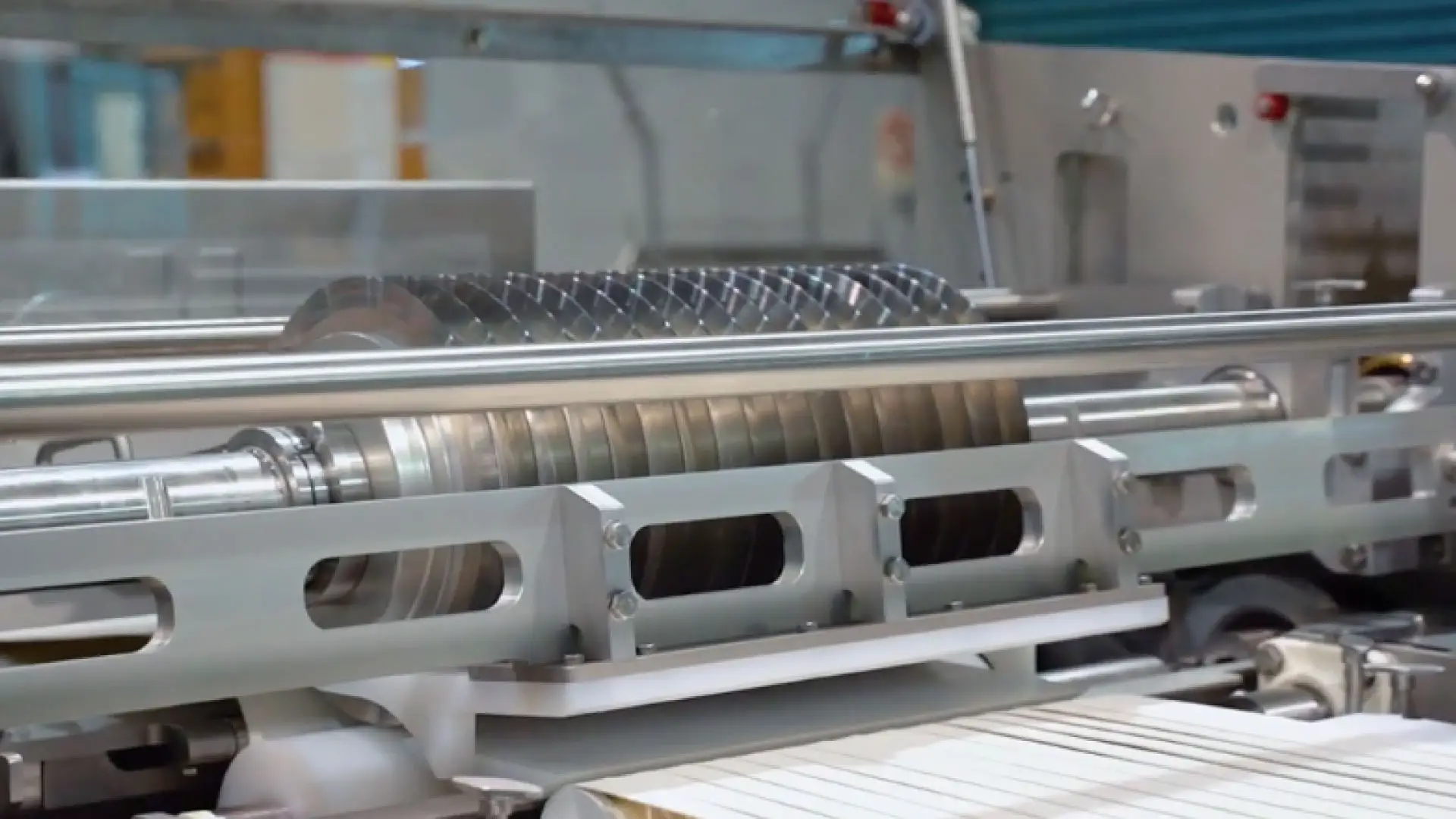 Industrial machine with geared rollers in manufacturing facility
