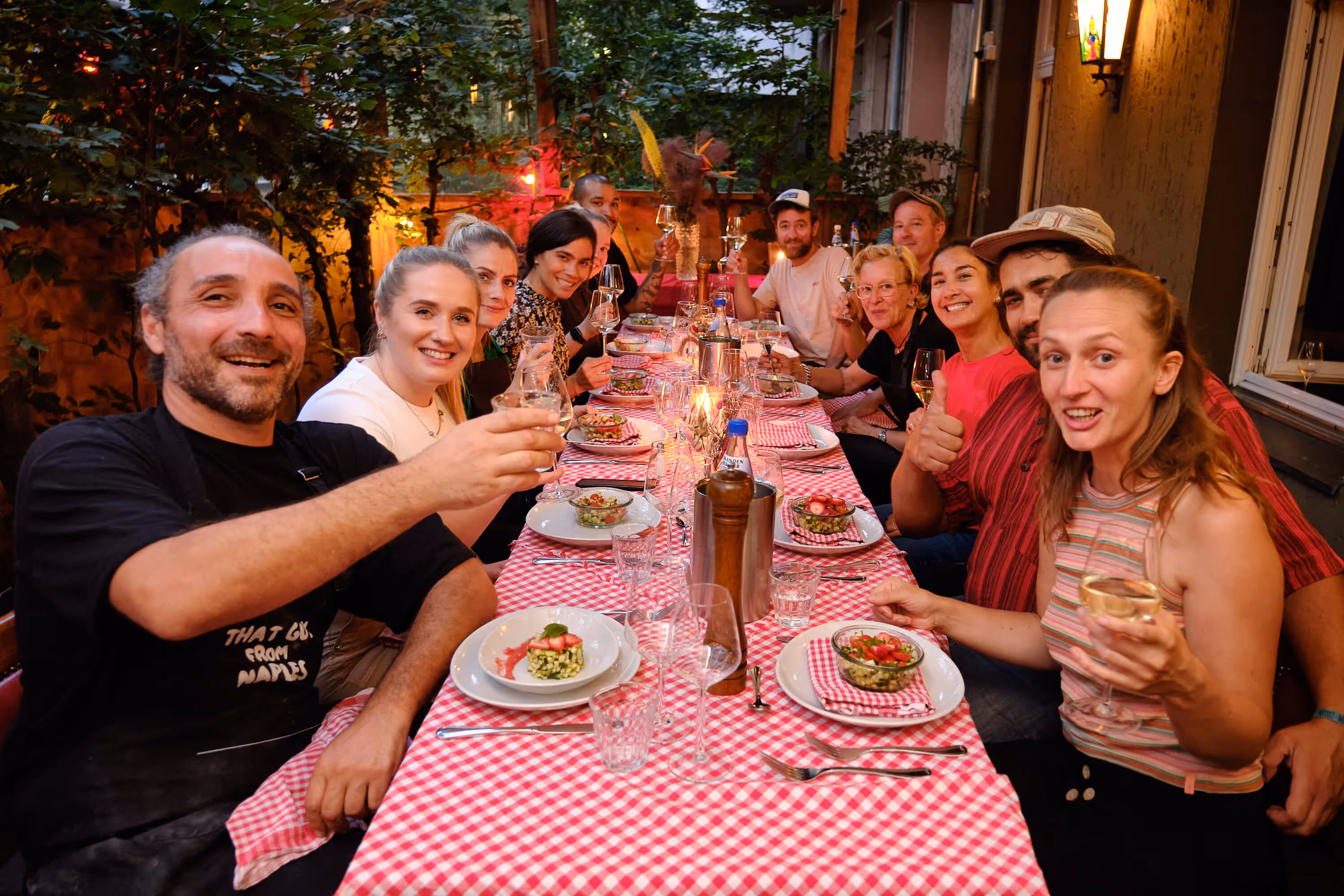 Gruppe von Menschen sitzt abends an einem gedeckten Tisch im Biergarten.
