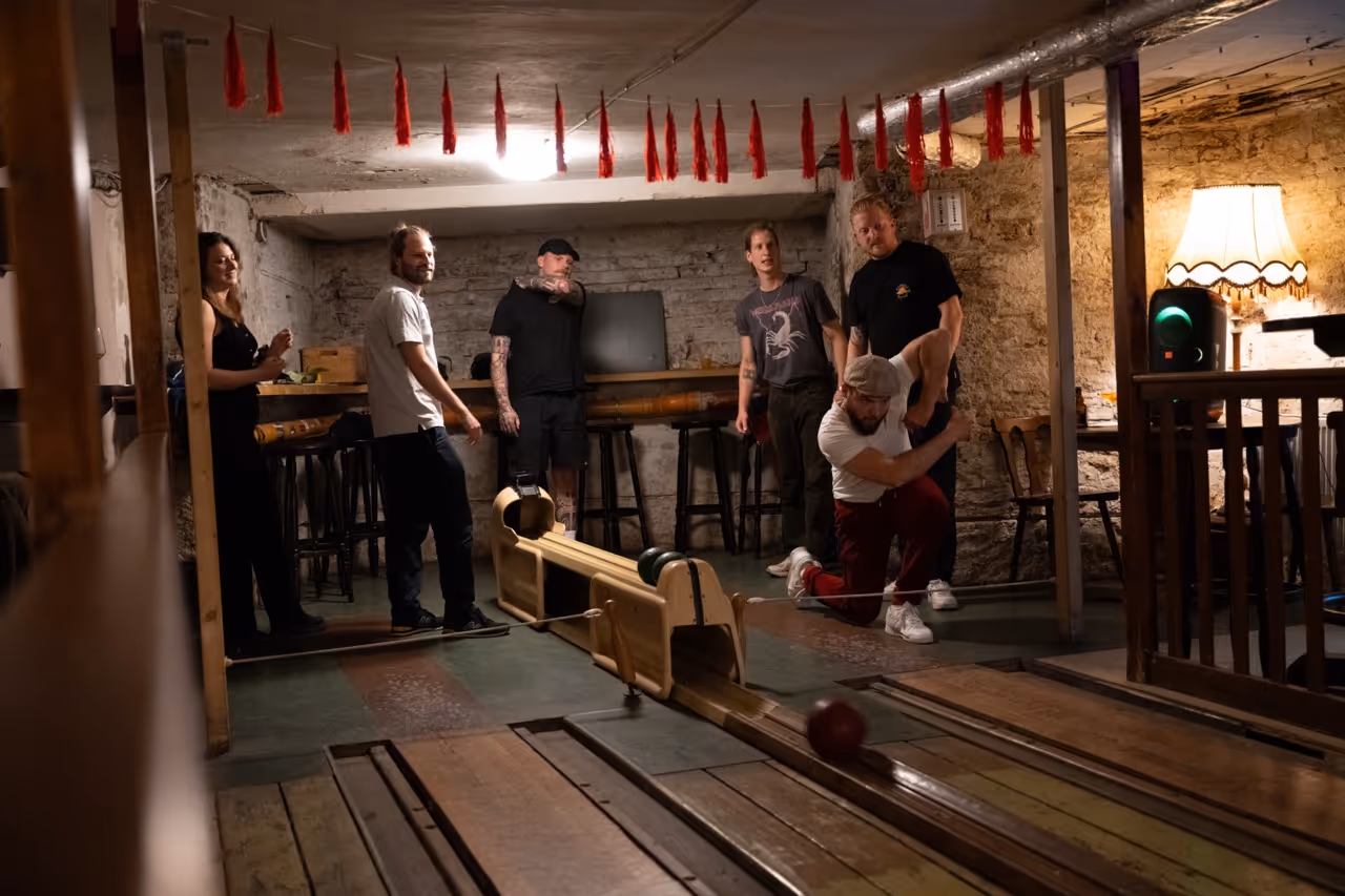 Menschen spielen Kegeln in einem gemütlichen, rustikalen Gasthaus.