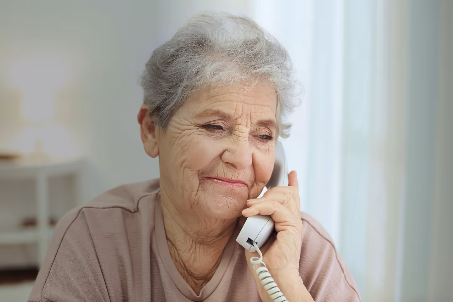 Smiling older woman with gray curly hair speaking on smartphone outdoors, wearing glasses – staying in touch with family
