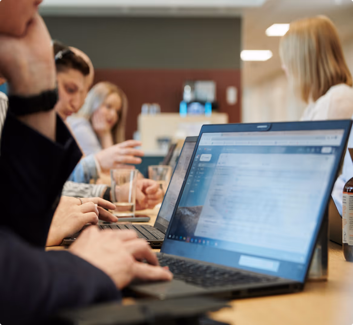 Büroangestellte sitzen an einem Großen Tisch und arbeiten
